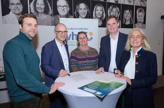 Fünf Personen stehen um einen Stehtisch im Foyer der Volkshochschule Bamberg Stadt