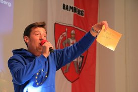 Ein Mann mit Mikrofon hält einen Zettel in die Luft