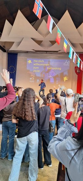 Junge Menschen von hinten, vorne auf der Bühne steht ein Rapper