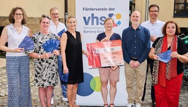 8 Personen: der Vorstand des Fördervereins übergibt einen Spenden-Scheck an Vertreter:innen der KulturTafel