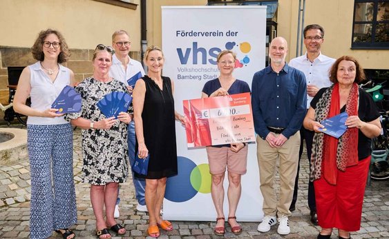 8 Personen: der Vorstand des Fördervereins übergibt einen Spenden-Scheck an Vertreter:innen der KulturTafel
