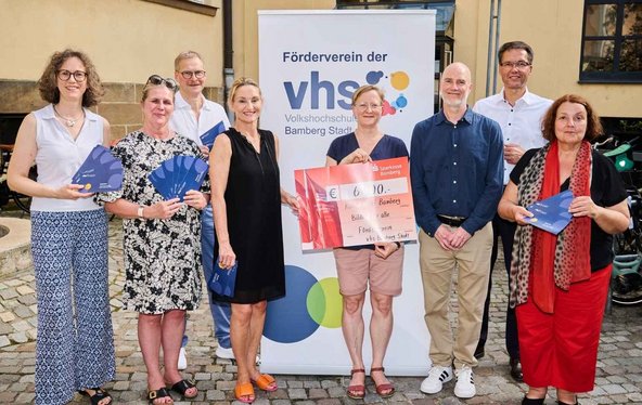 8 Personen: der Vorstand des Fördervereins übergibt einen Spenden-Scheck an Vertreter:innen der KulturTafel