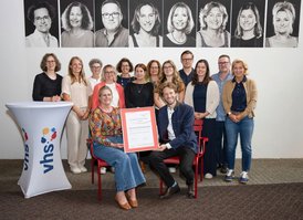 vhs-Leitung Dr. Anna Scherbaum und Oberbürgermeister Sebastian M. Niedermaier halten die Urkunde des 3-Sterne-Assessments in den Händen. Dahinter das vhs-Team